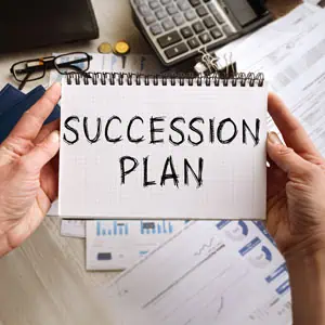 Hands holding a notebook with 'Succession Plan' written on it